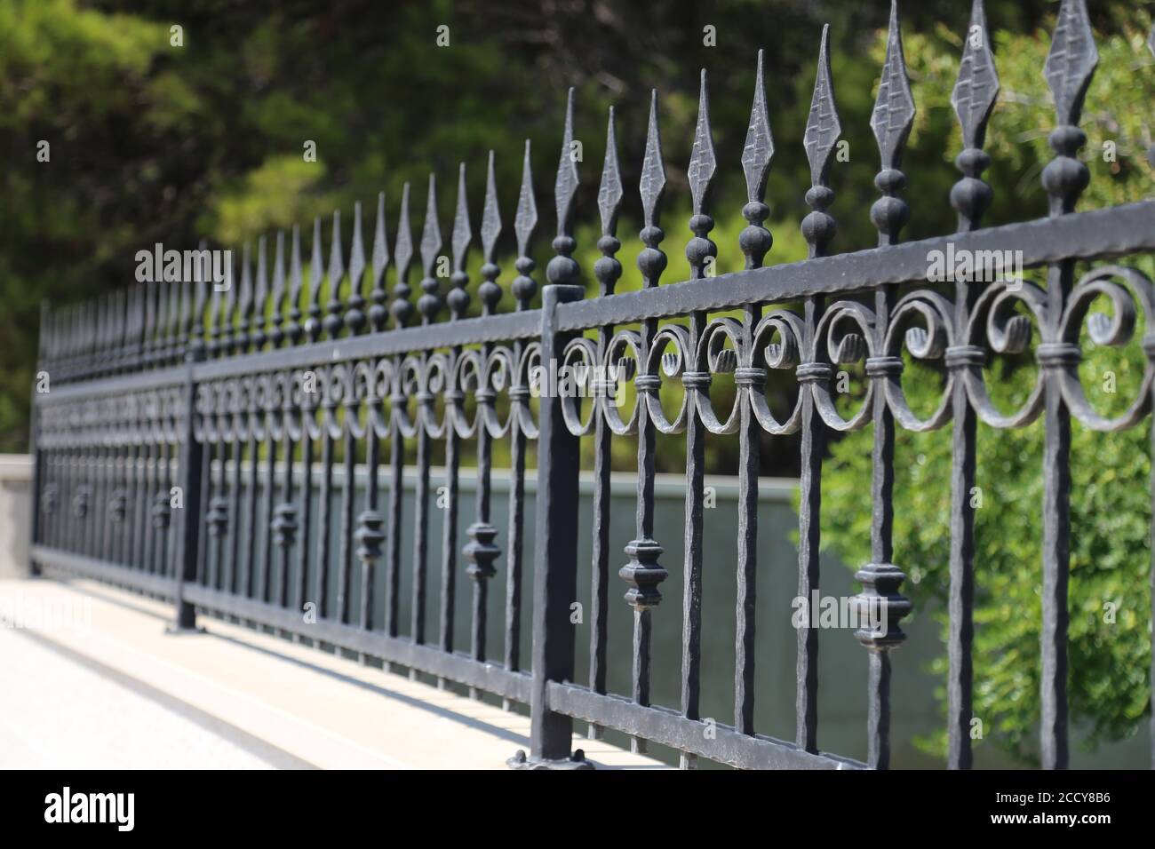 Black iron wrought fence of a park with ornate design. Stock Photo