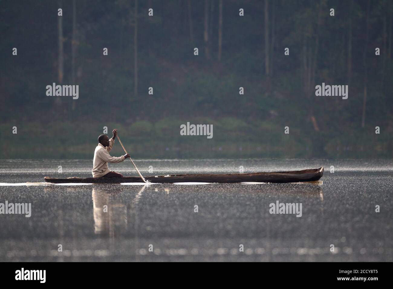 Man paddling in dugout canoe on a lake, Kisoro, Uganda, East Africa Stock Photo