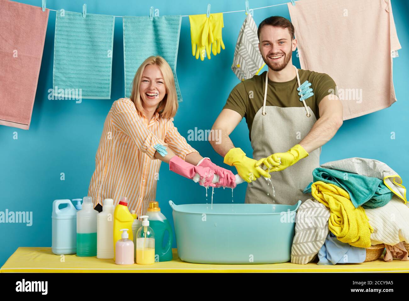 laughing woman and man in casual clothes putting, stretching towel while standing behind the
