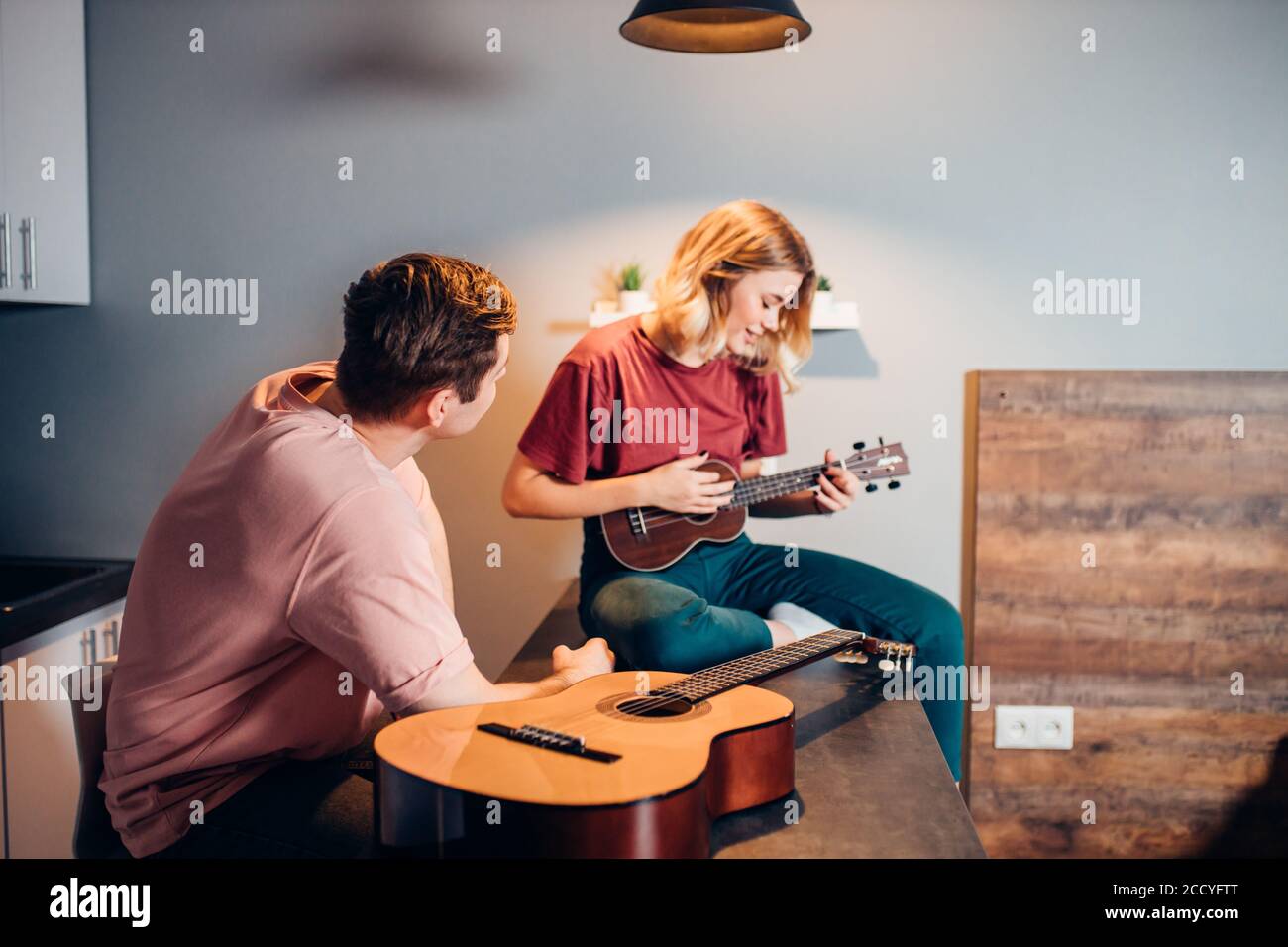 cute girl with blond short hair professionally play ukulele at home
