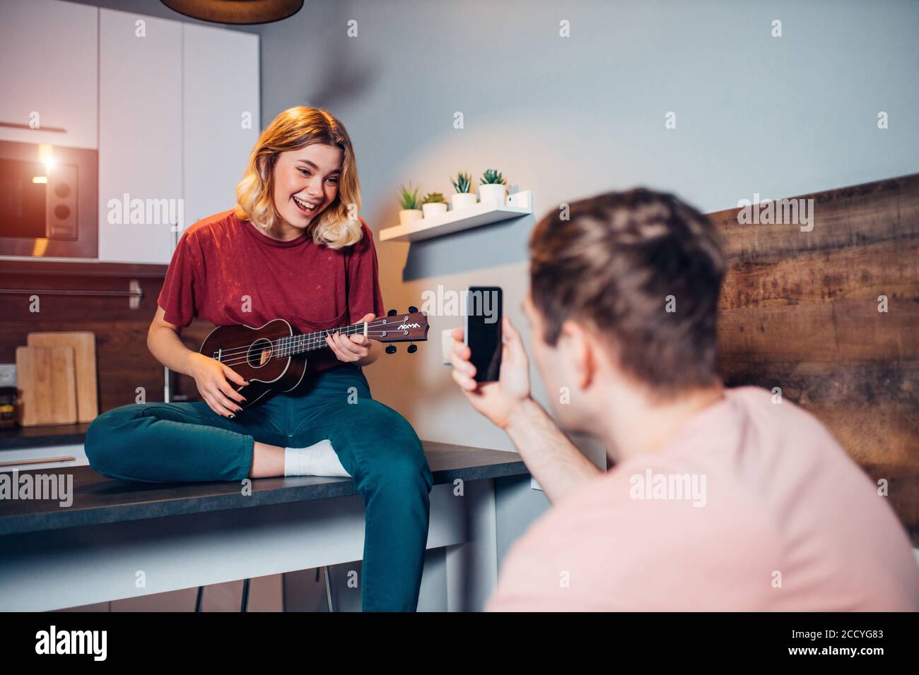 cute girl with blond short hair professionally play ukulele at home