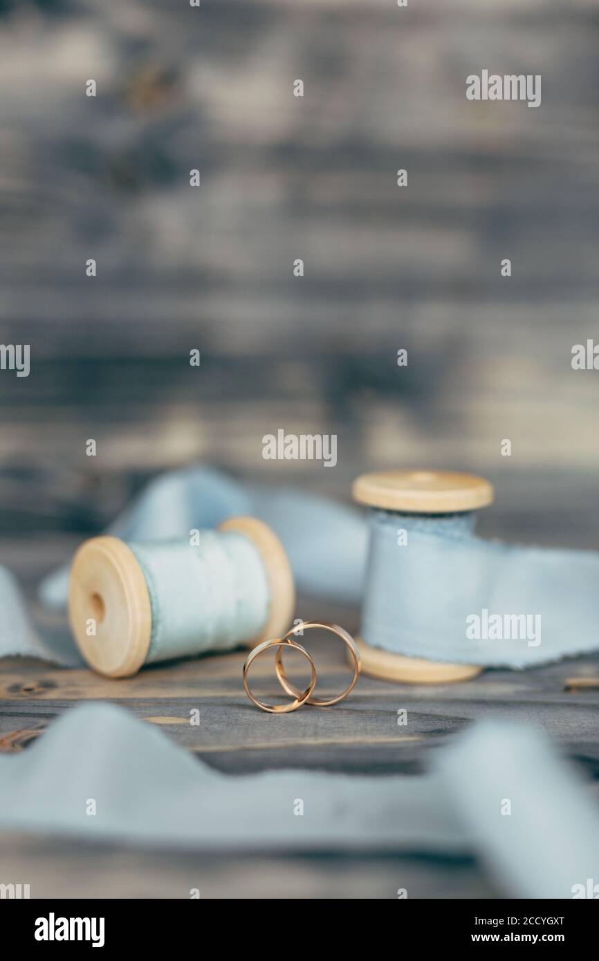 Two gold wedding rings in an upright position with spools of ribbons on