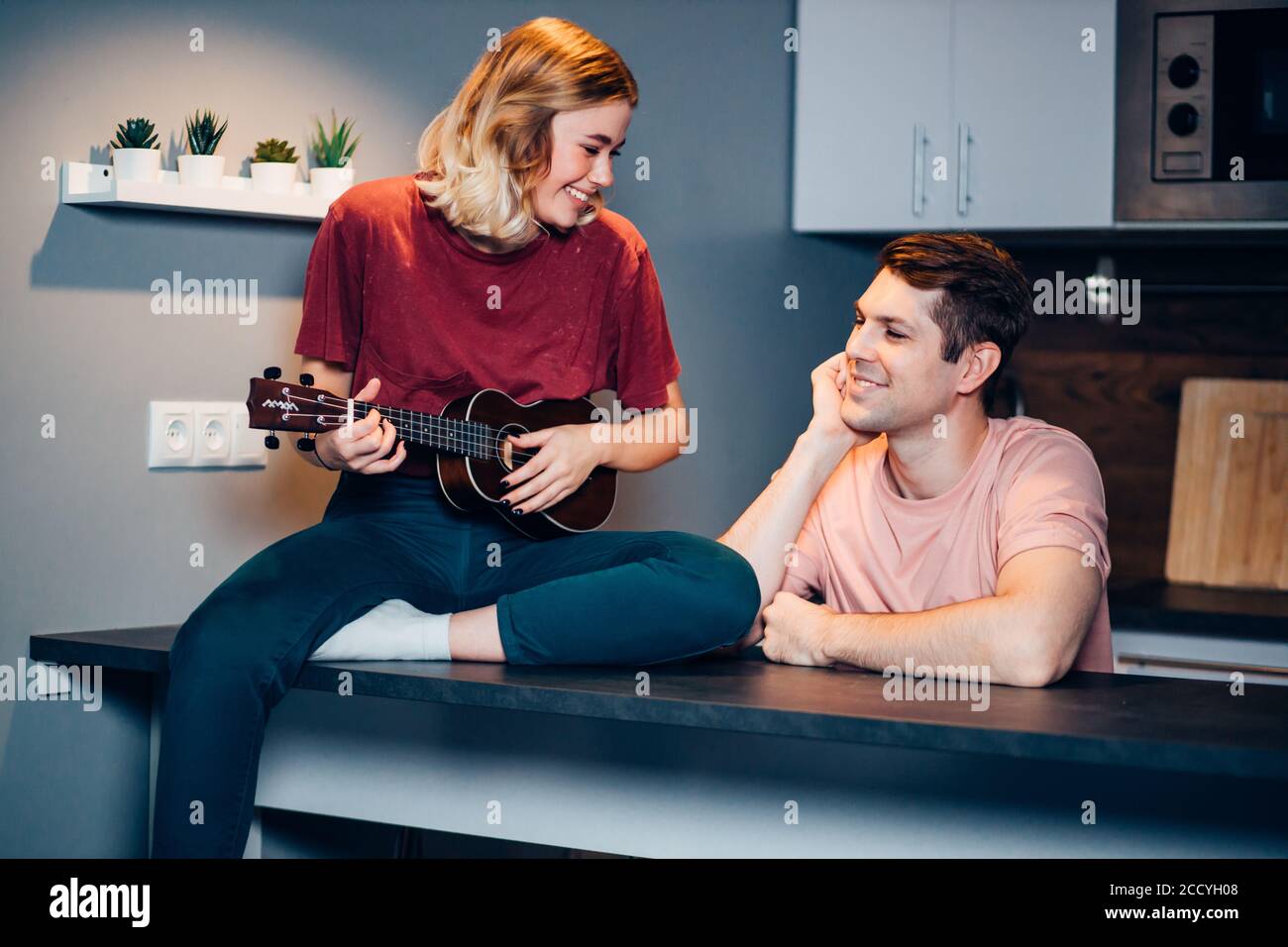 cute girl with blond short hair professionally play ukulele at home