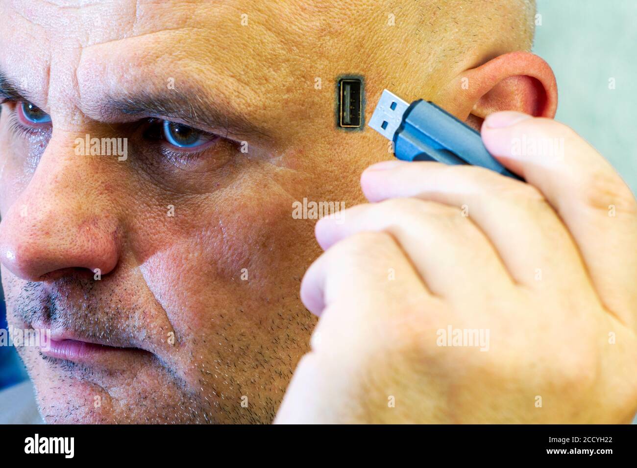 concept computerization chipization computer addiction a man inserts a flash drive into his head a USB connector is located on his head Stock Photo