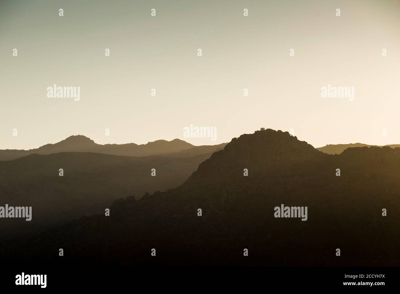 Mountains shapes fading gradually on the horizon at sunset. Soft shadows and golden light. Stock Photo