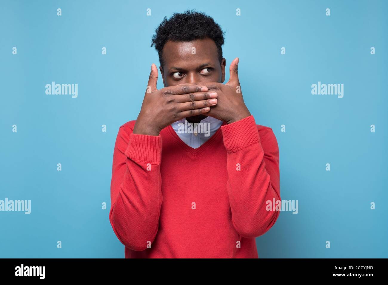 African man covering his face by hand and peeping at camera Stock Photo ...