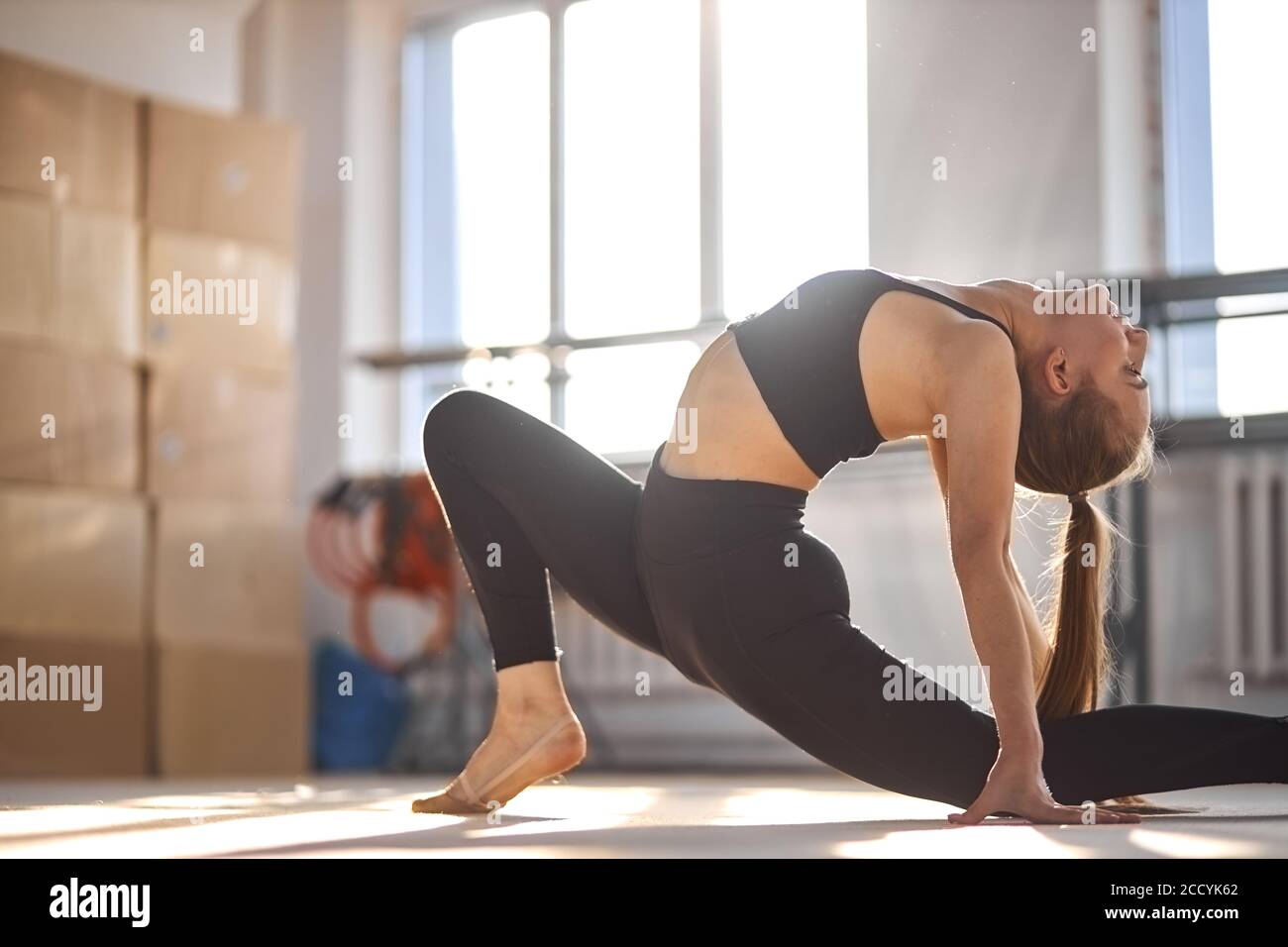 portrait of young charming gymnast bending crab, stretching body back intensively, looks up, health life style concept Stock Photo