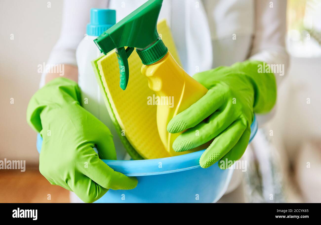 Cleaning lady with gloves carries different cleaning products as