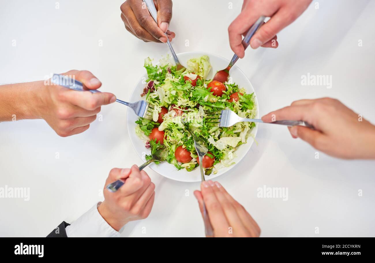 Hands with forks of business team while eating salad for healthy eating