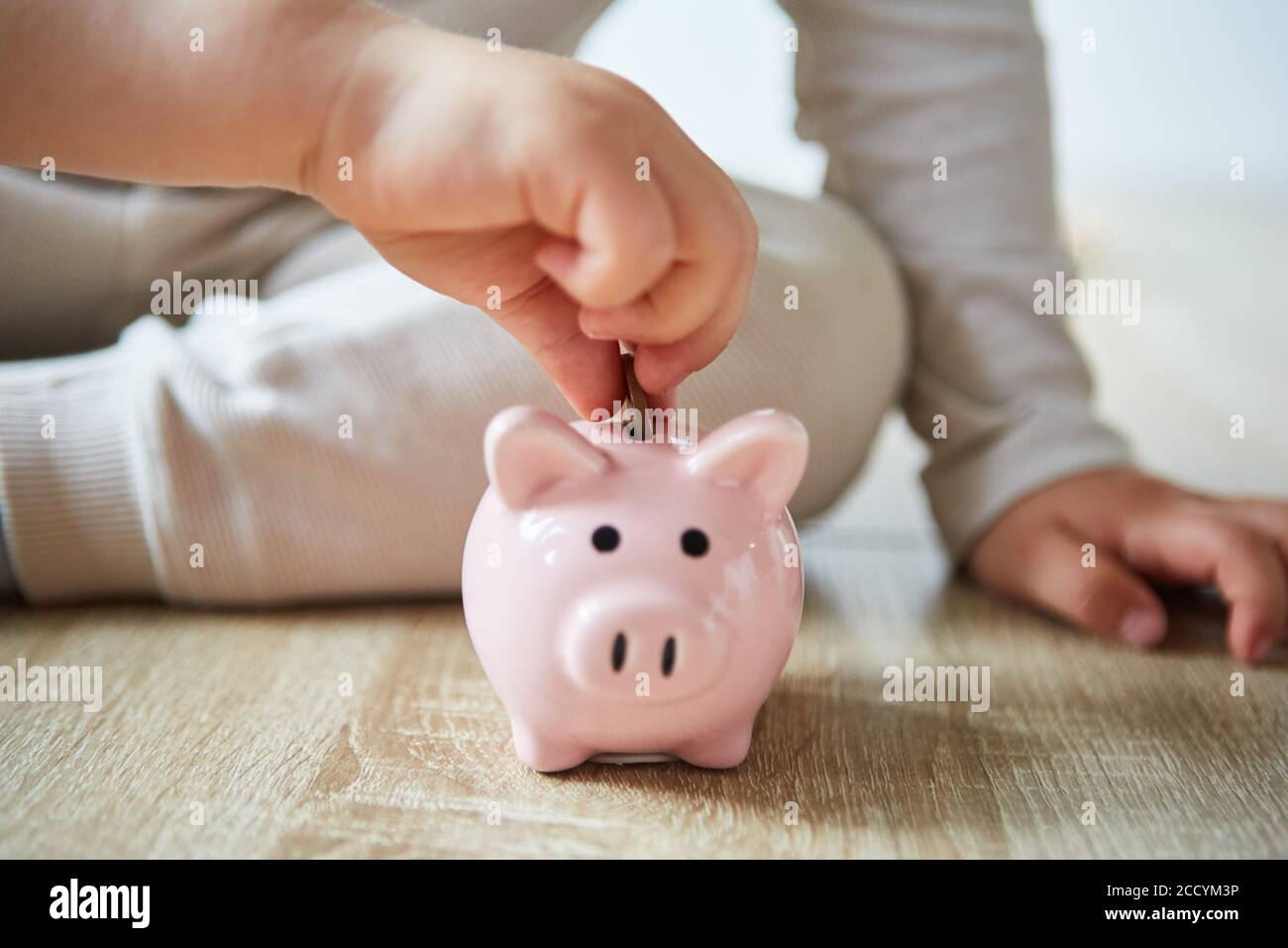 Children's hands put a coin in a piggy bank and save their pocket money Stock Photo