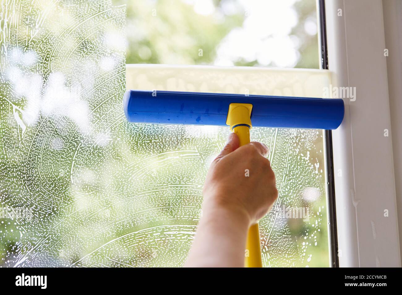 Hand of window cleaner when cleaning windows with wiper and soapy water