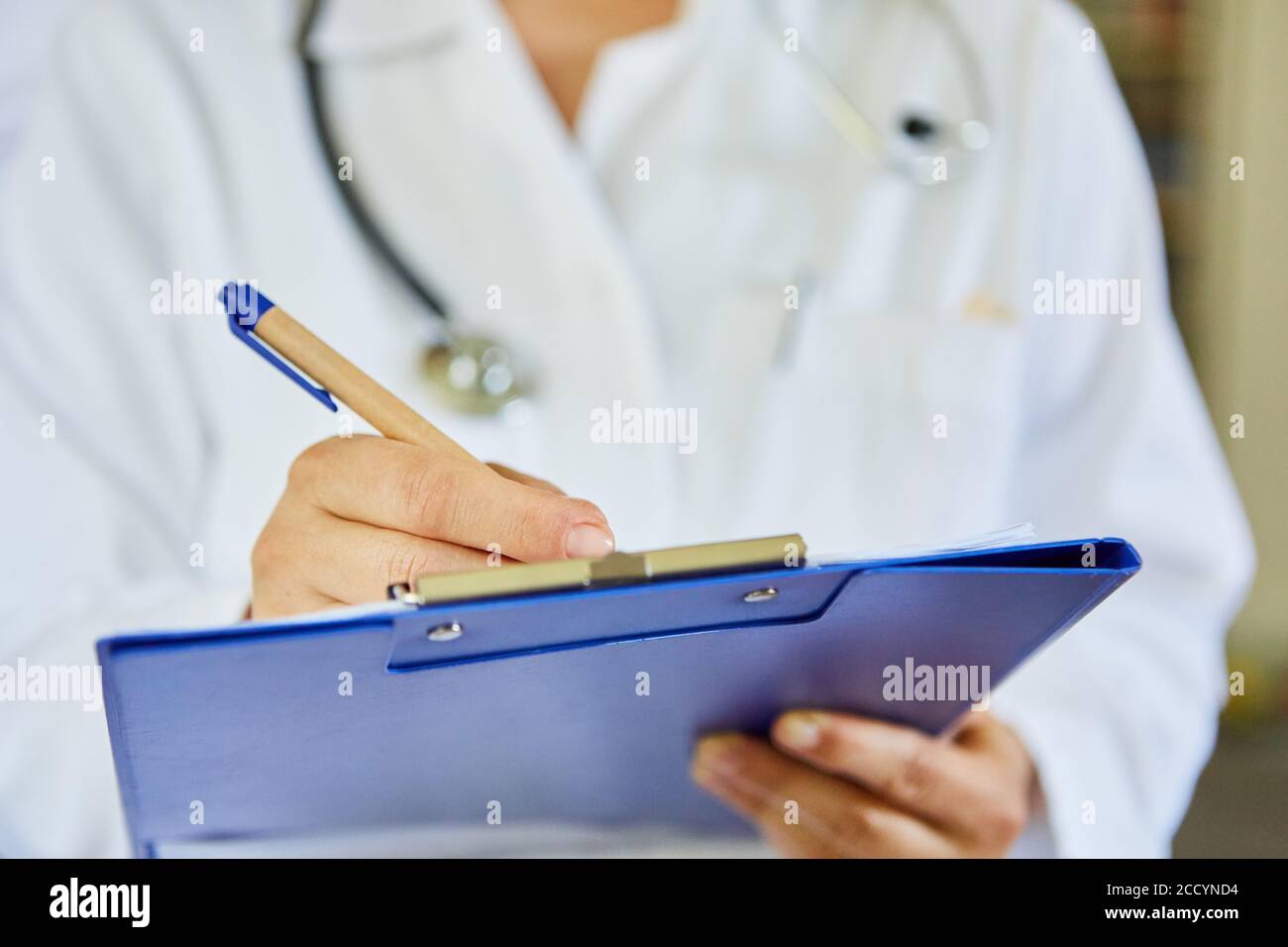 Female doctor with clipboard and pen writes diagnostic notes for the medical record Stock Photo