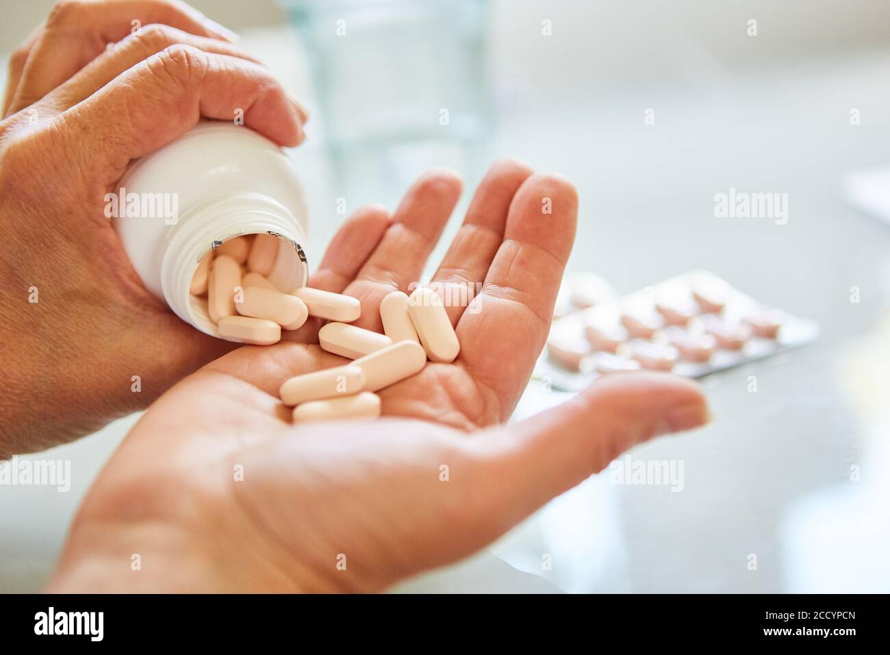 Patient pours many pills on his hand as a sign of drug addiction Stock Photo