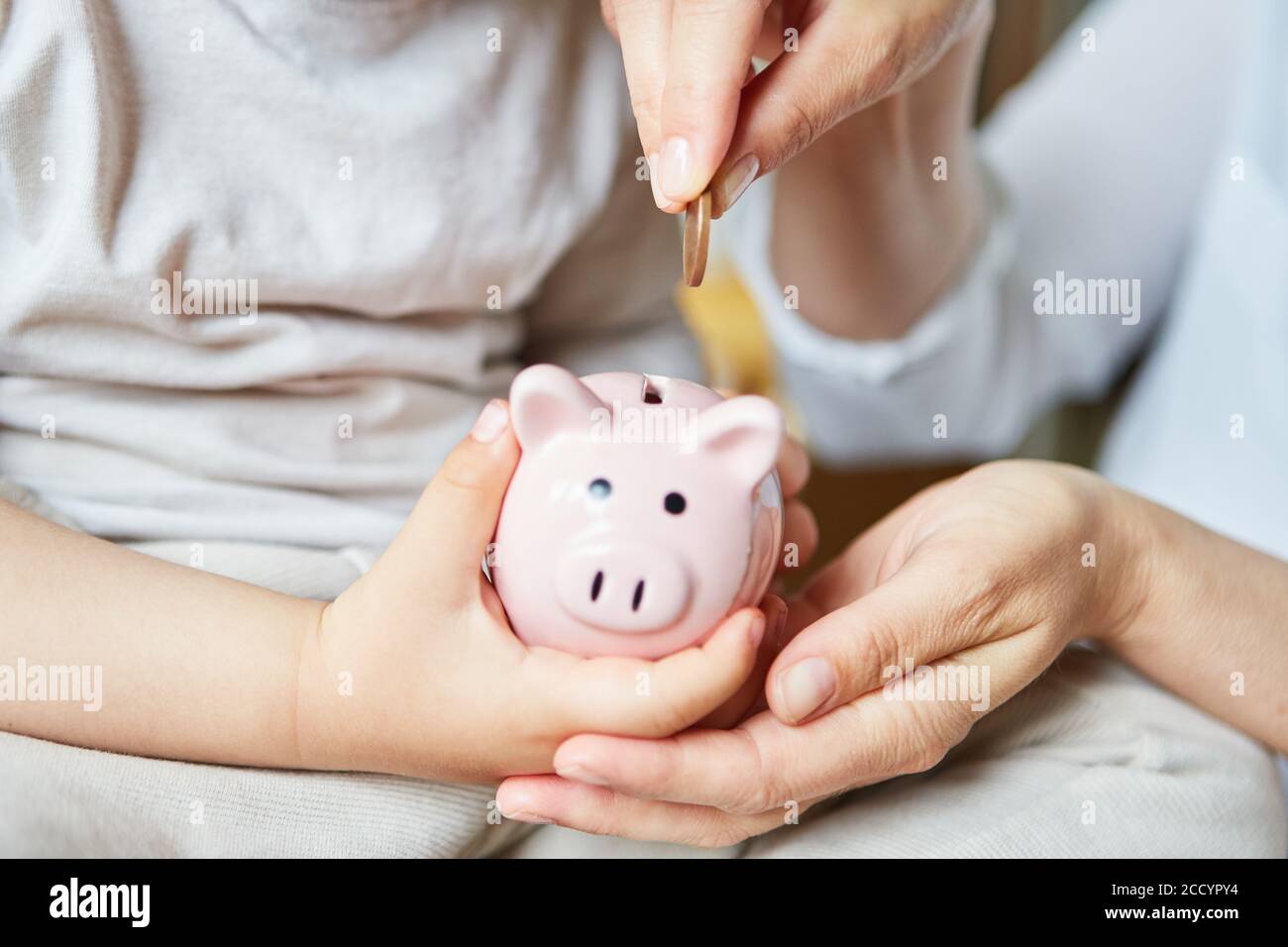 Mother and child put a coin into the pink piggy bank together Stock ...