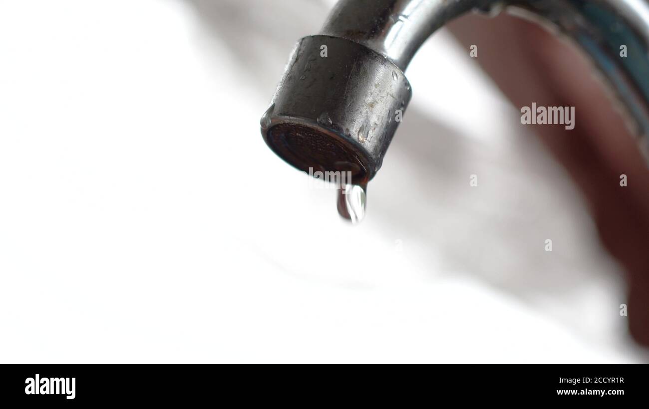 The old tap on the kitchen mixer is leaking. Tap water dripping. Daylight macro photography Stock Photo