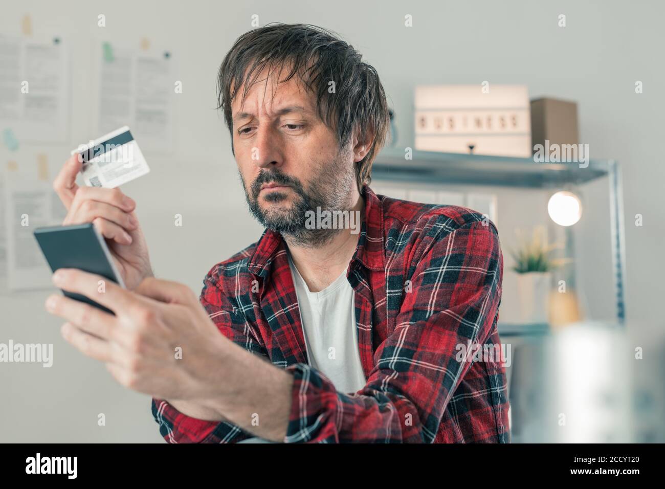 Freelancer shopping online with smartphone app and credit card from small business home office, selective focus Stock Photo