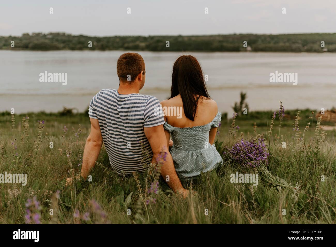 Young woman and man are sitting on the bank of the river Stock Photo ...