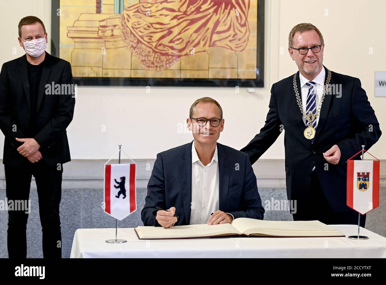 Berlin, Germany. 25th Aug, 2020. Michael Müller (SPD, m), Berlin's governing mayor, signs the district's book, while Reinhard Naumann (SPD, r), district mayor of Berlin's Charlottenburg-Wilmersdorf district, and Klaus Lederer (Die Linke), Berlin's Senator for Culture and Europe, stand behind him. Credit: Britta Pedersen/dpa-Zentralbild/dpa/Alamy Live News Stock Photo