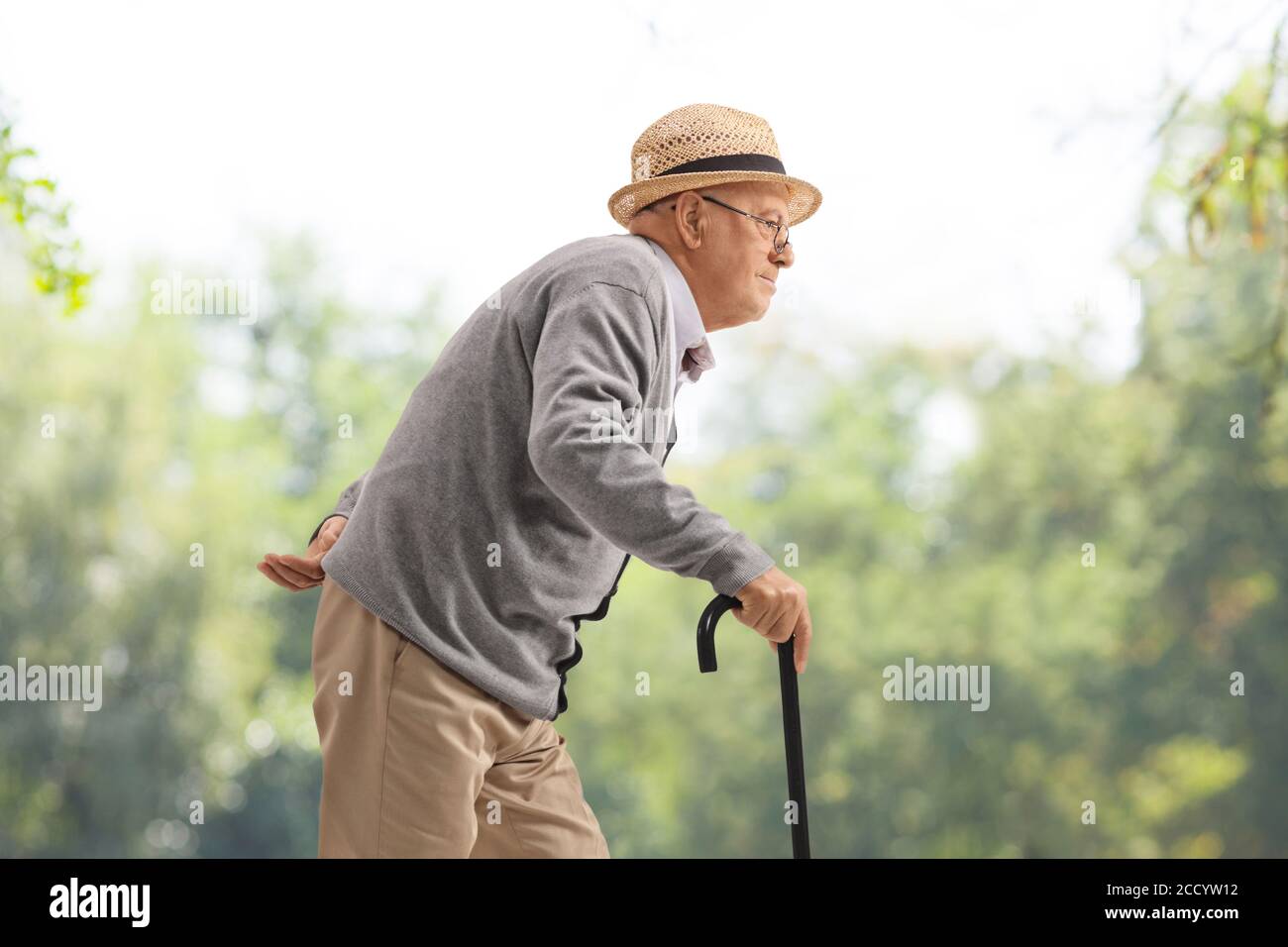 Elderly man walking with a cane in a park Stock Photo