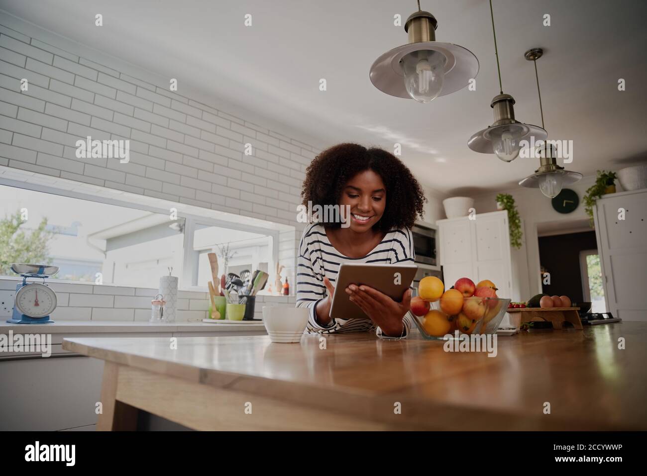 Cheerful young african woman browsing internet on digital tablet for ...