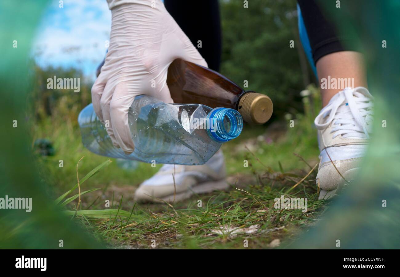 Volunteer collecting bottles in the forest. View from the neck of the