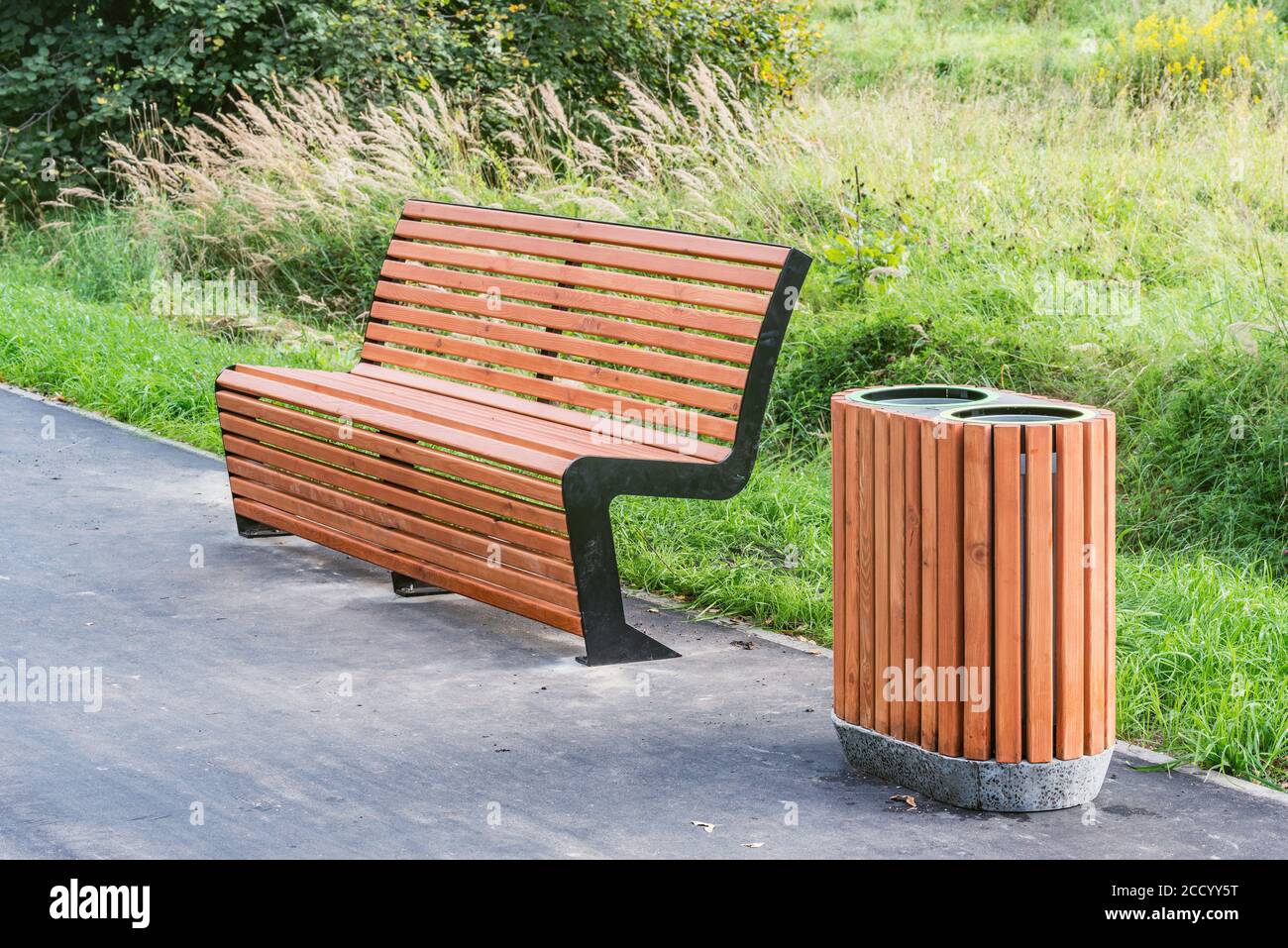 Bin for waste collection wooden bench in the city park at sunset time