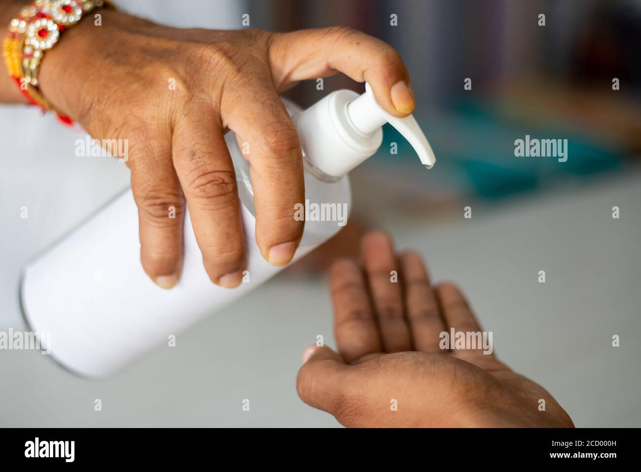 Close up of Shopkeeper Hands giving sanitizer to customer to stop spreading coronavirus or covid-19 infection - concept of safety, hygiene measures at Stock Photo