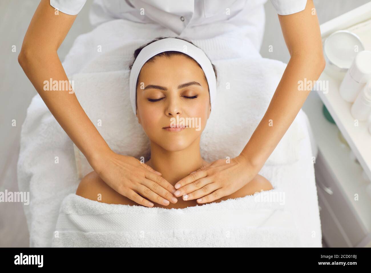 Cosmetologist or masseur making massage of upper shoulder girdle for woman in beauty salon Stock Photo