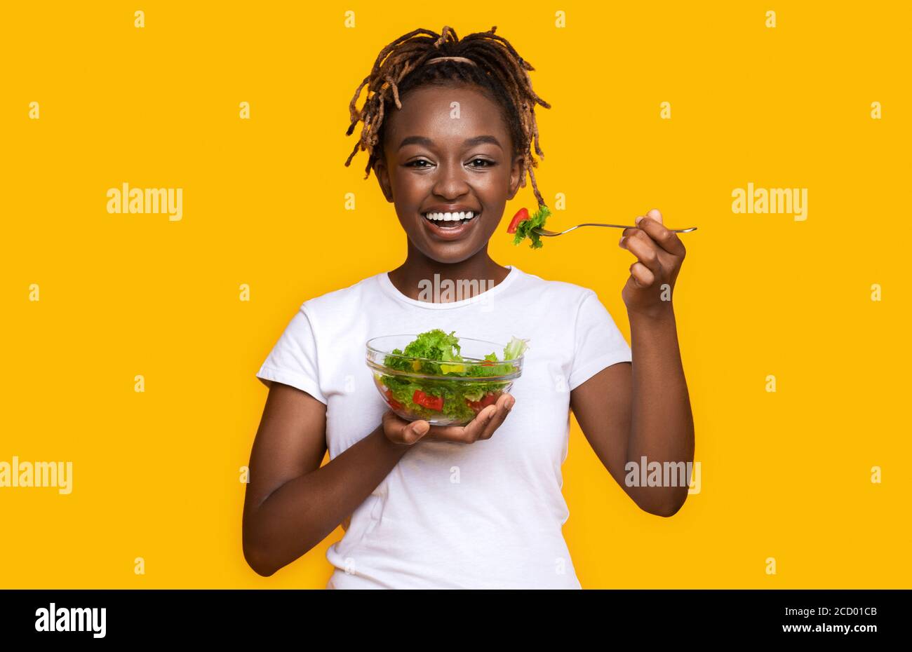 Healthy black girl eating fresh salad over yellow Stock Photo - Alamy