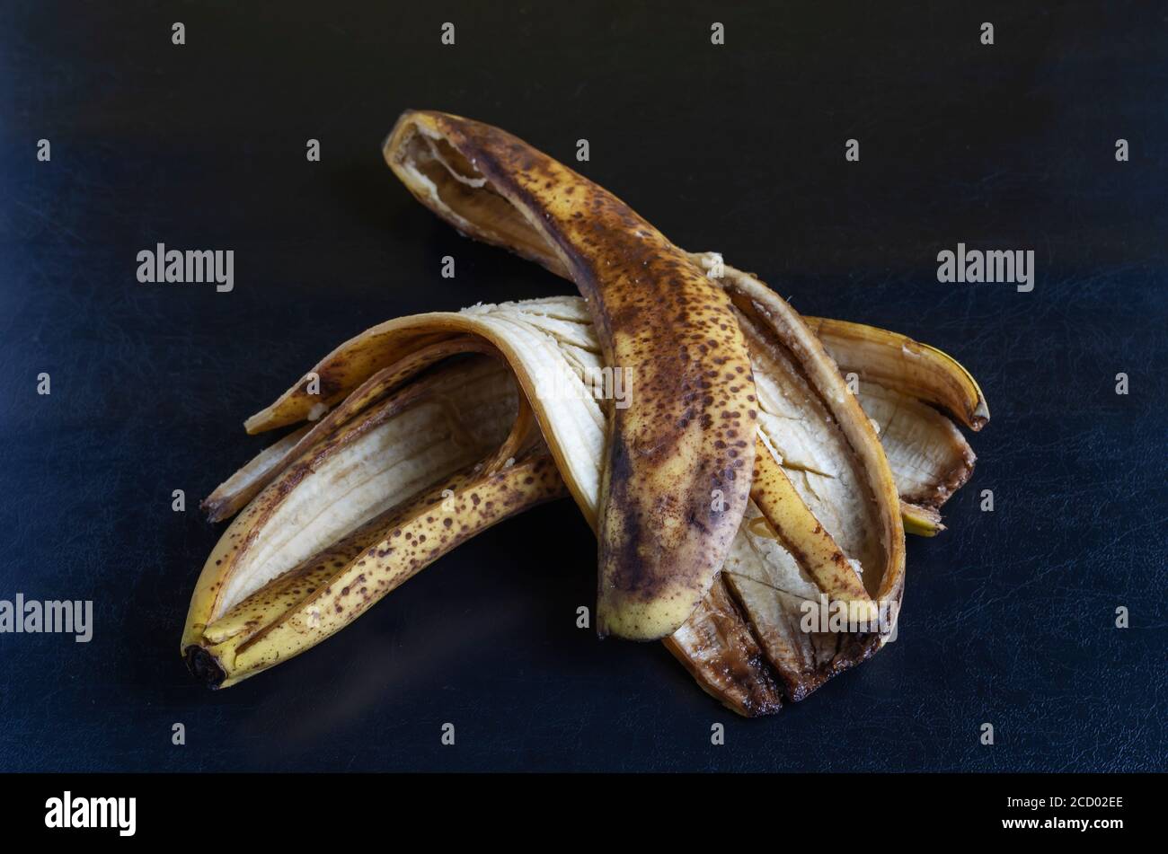 Detailed photo Discarded banana peel on black background. The peel of overripe bananas with