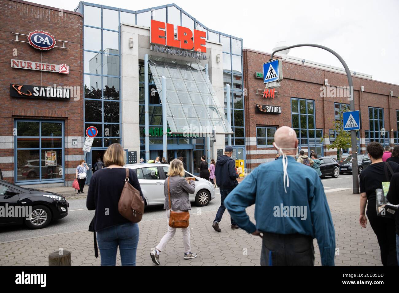 Hamburg, Germany. 25th Aug, 2020. After a fire alarm, passers-by and employees stand in front of an entrance to the Elbe Einkauzentrum (EEZ). Due to heavy smoke development in the basement, the Elbe shopping centre in Hamburg-Osdorf was evacuated at noon on Tuesday. Credit: Christian Charisius/dpa/Alamy Live News Stock Photo