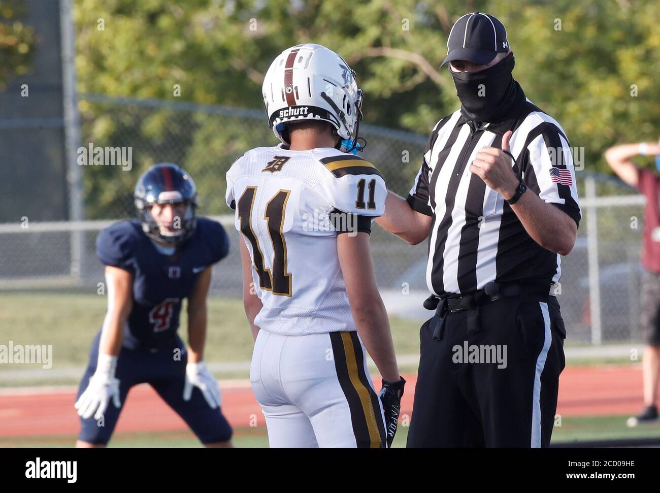 A masked official talks to a Davis Darts Jackson Leaver (11) before a kick off between two high school teams the Herriman Mustangs and Davis Darts, the first regular season football game in the United States since the coronavirus disease (COVID-19) pandemic began, at Herriman High School in Herriman, Utah, U.S. August 13, 2020.  REUTERS/George Frey Stock Photo