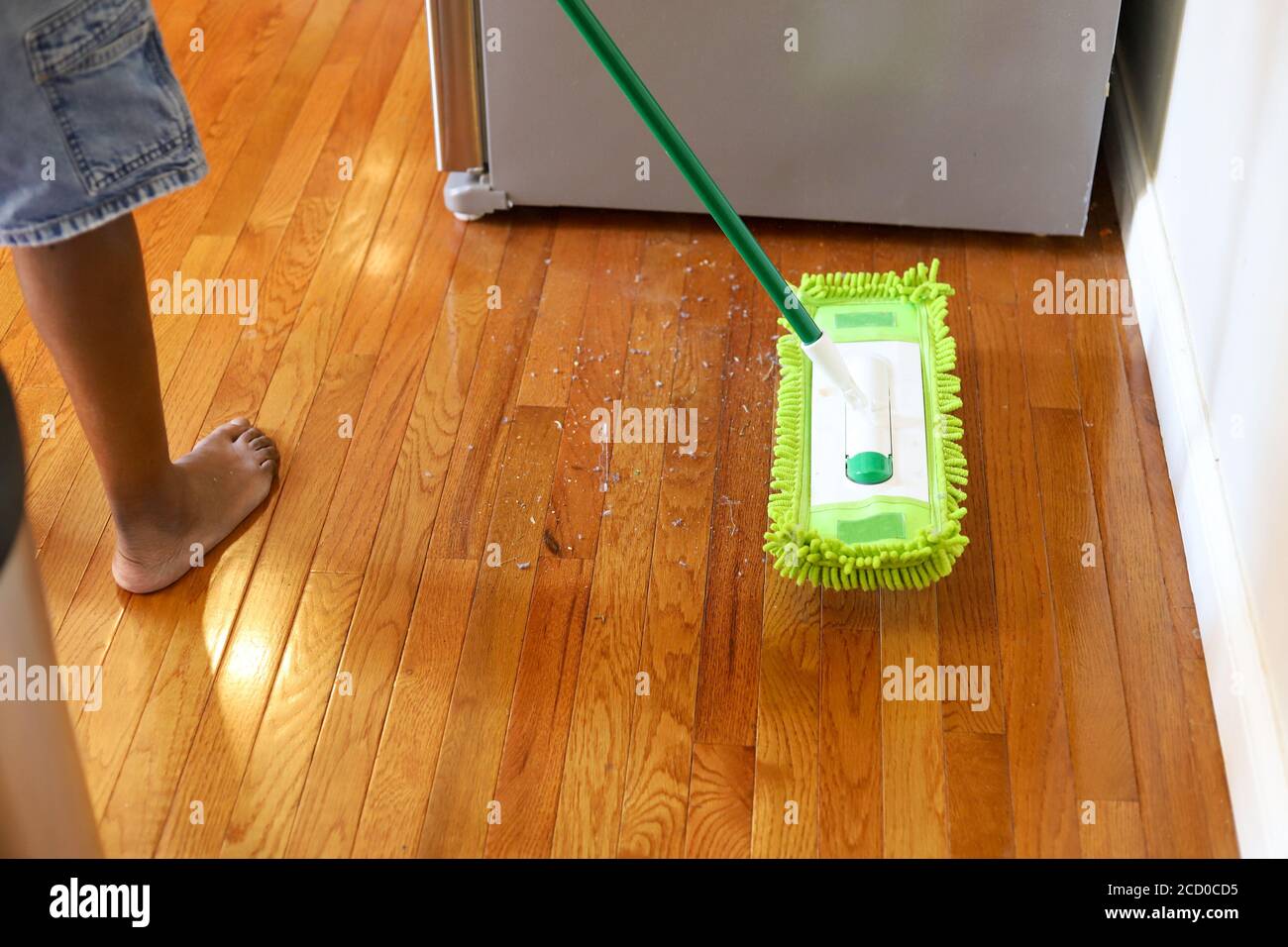 An African-American man dusting hardwood flooring in a residential kitchen Stock Photo