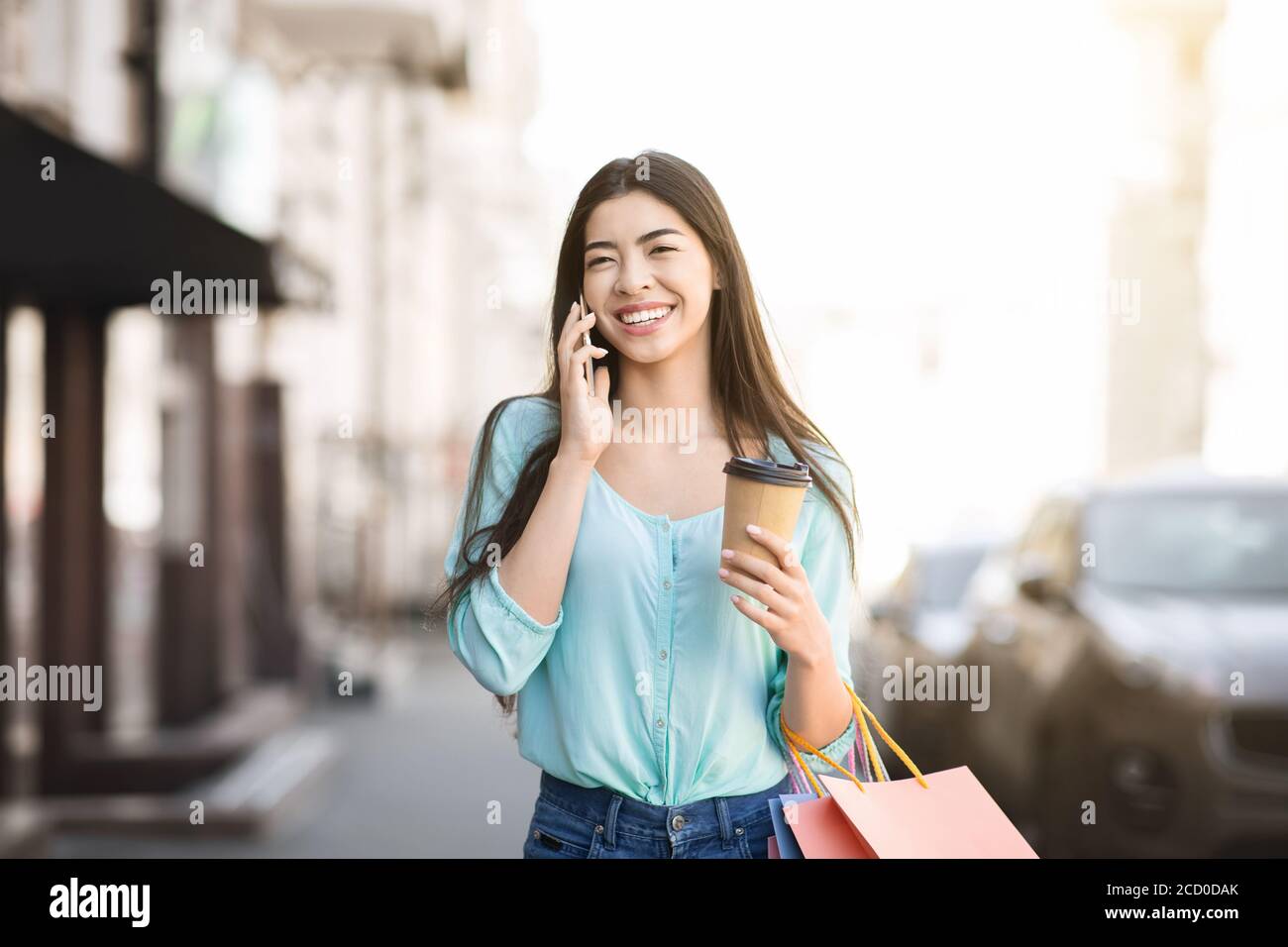 AsianWoman Walking With Shopper Bags And Coffee And Talking On Celphone Stock Photo