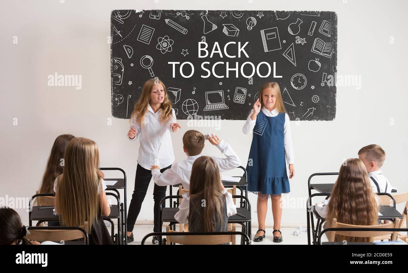 School children in classroom at lesson with worlds Back to school on classboard. Back to school, education, learn, lifestyle, childhood concept. Cheerful girls and boys during first studying day. Stock Photo