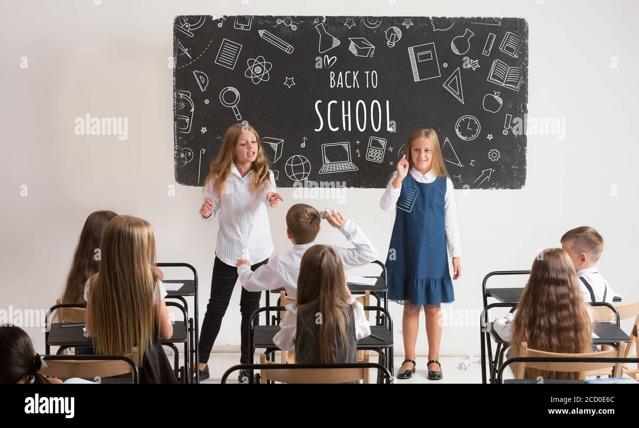 School children in classroom at lesson with worlds Back to school on classboard. Back to school, education, learn, lifestyle, childhood concept. Cheerful girls and boys during first studying day. Stock Photo