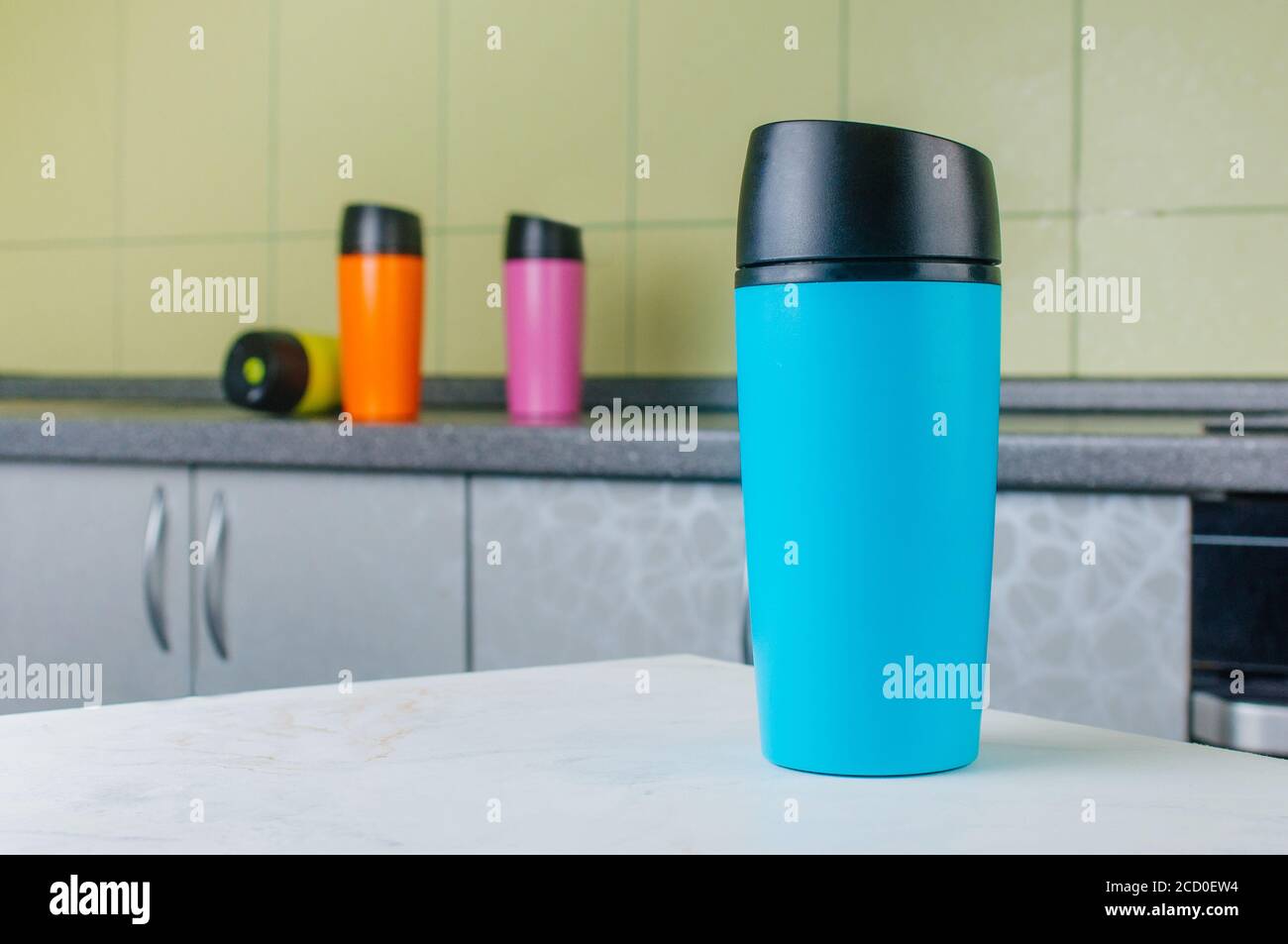 Blue thermo mug on the table in the kitchen. Stock Photo