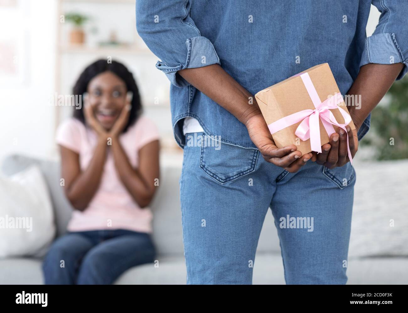 Man holding present behind back for his surprised girlfriend Stock Photo