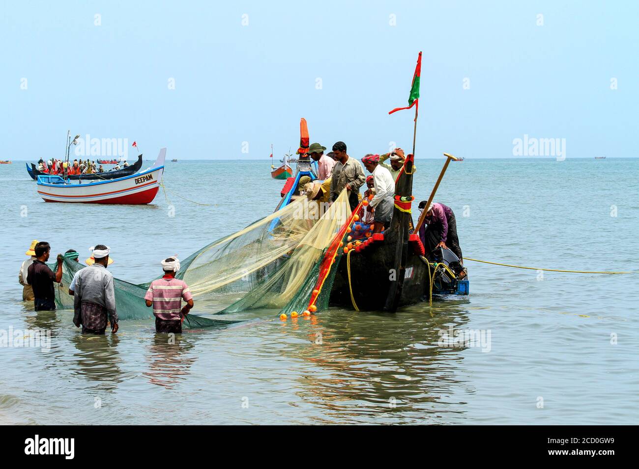 https://c8.alamy.com/comp/2CD0GW9/life-of-traditional-fishing-people-in-kerala-wooden-fisherman-boat-fisherman-throwing-the-net-in-the-seashore-fisherman-repairs-fishing-net-2CD0GW9.jpg