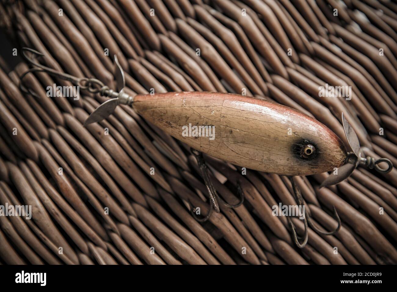 An old South Bend fishing lure, or plug, designed for catching predatory fish photographed against the whicker lid of an old tackle box. From a collec Stock Photo