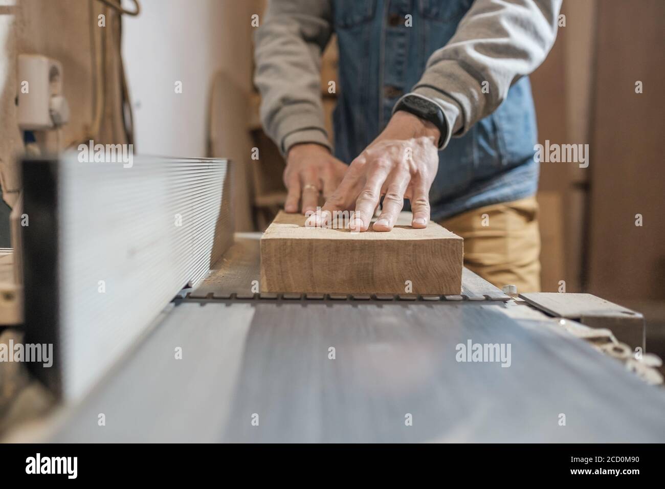 Carpenter in the workshop processes wood planks on a grinder Stock Photo