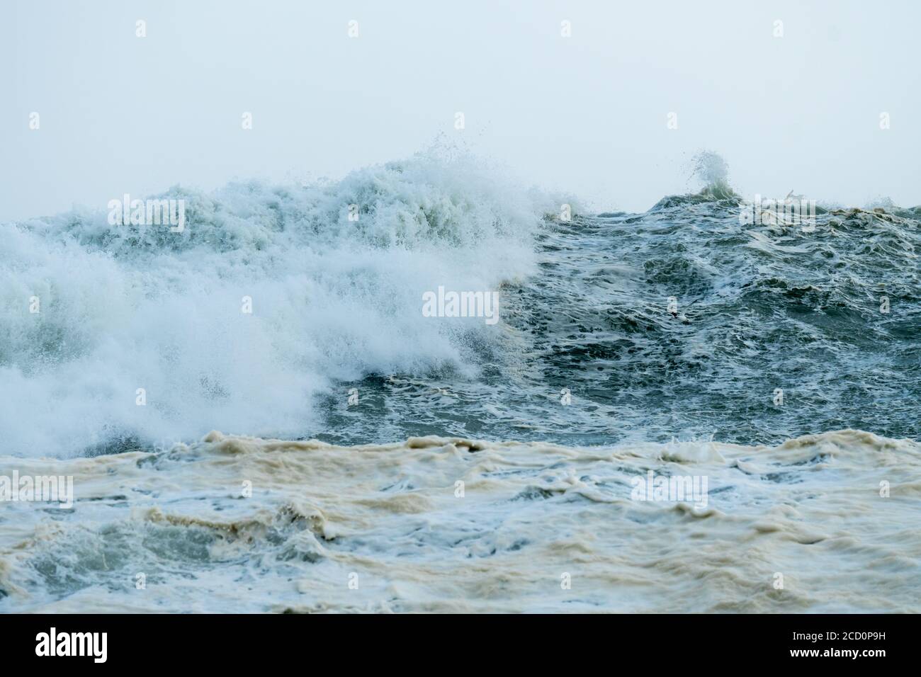 close up of high seas and waves crashing during a storm in Winter with sea foam or spume on the ocean surface which is algal bloom concept weather Stock Photo