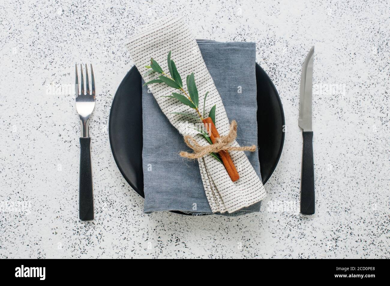 Holiday elegant table setting with linen napkin, sprig and cinnamon. Top view, flat lay. Stock Photo