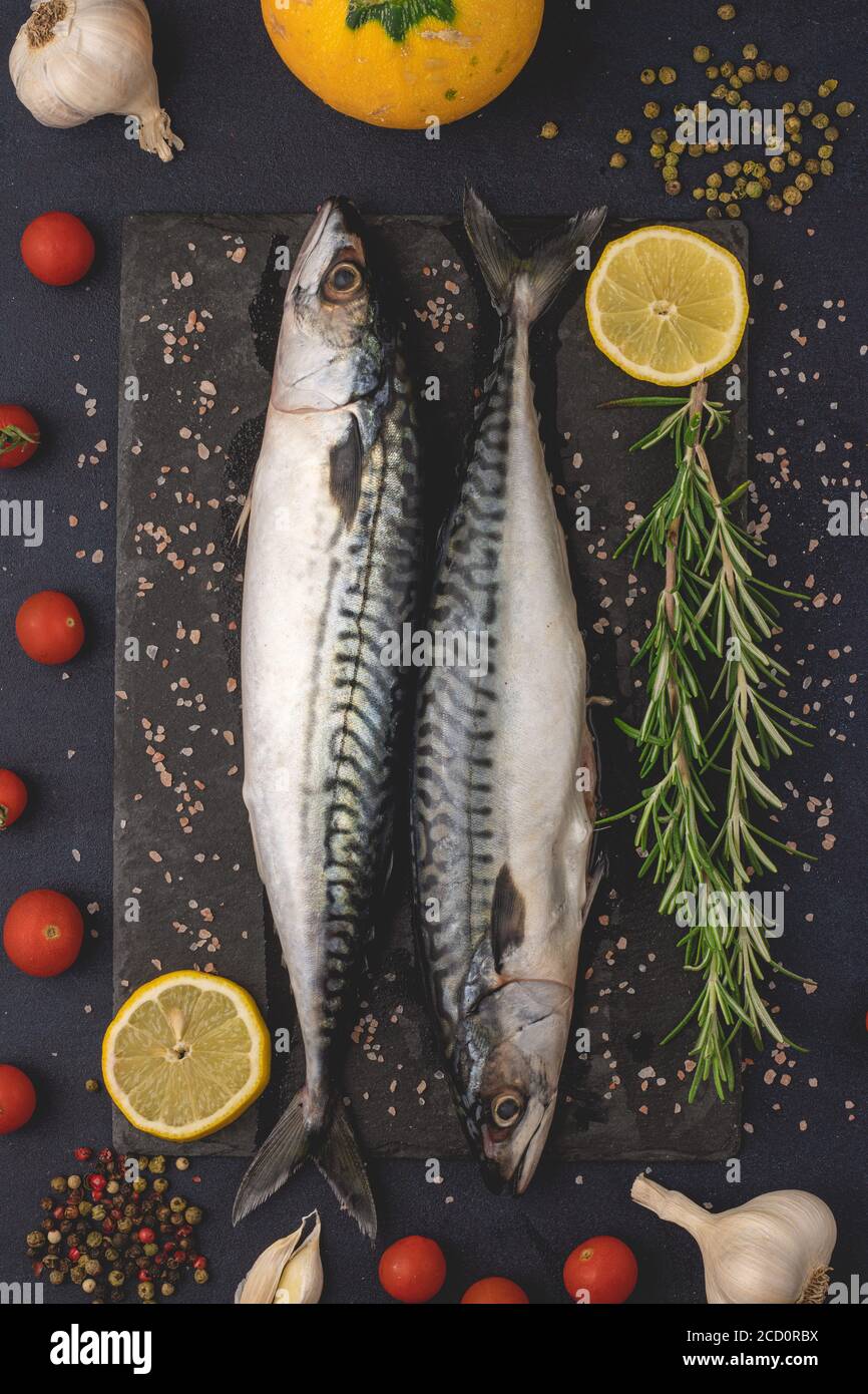Fresh raw mackerels with salt, garlic, pepper and lemon. Healthy Mediterranean food and dieting concept, top view, flat lay. Stock Photo