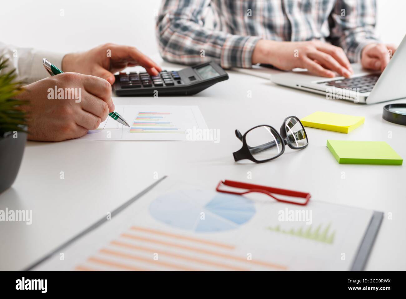 Documents with chart and graph and pen on background of two employees working Stock Photo
