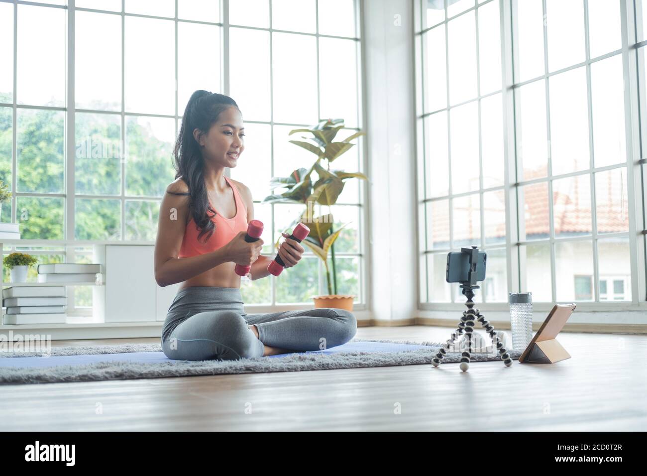 Training at home. Young asian woman exercise with dumbbell while online