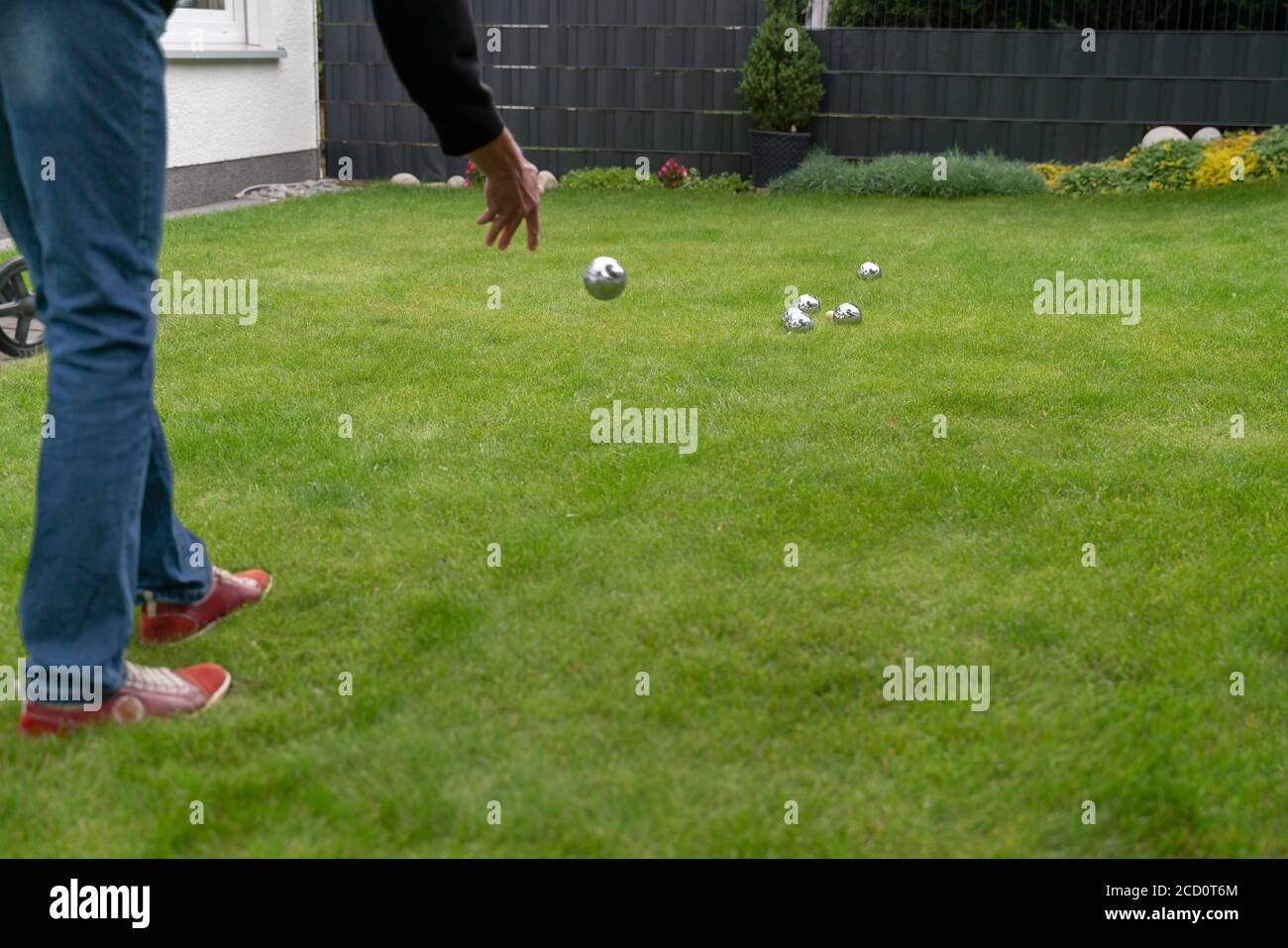 Boccia balls made of chromed steel lie on a grass surface. Woman playing boccia in the garden. Stock Photo