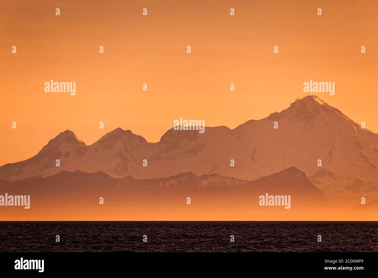 Mount Iliamna in golden orange at sunset, Kenai Peninsula, South-central Alaska in summertime; Ninilchik, Alaska, United States of America Stock Photo