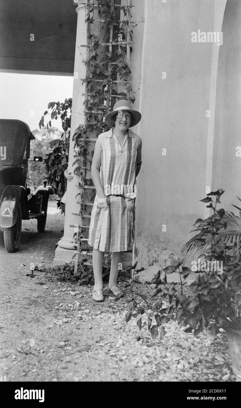 Vintage 1920s English black and white photograph showing a young woman, outside, posing in fashionable clothes of the day. Stock Photo