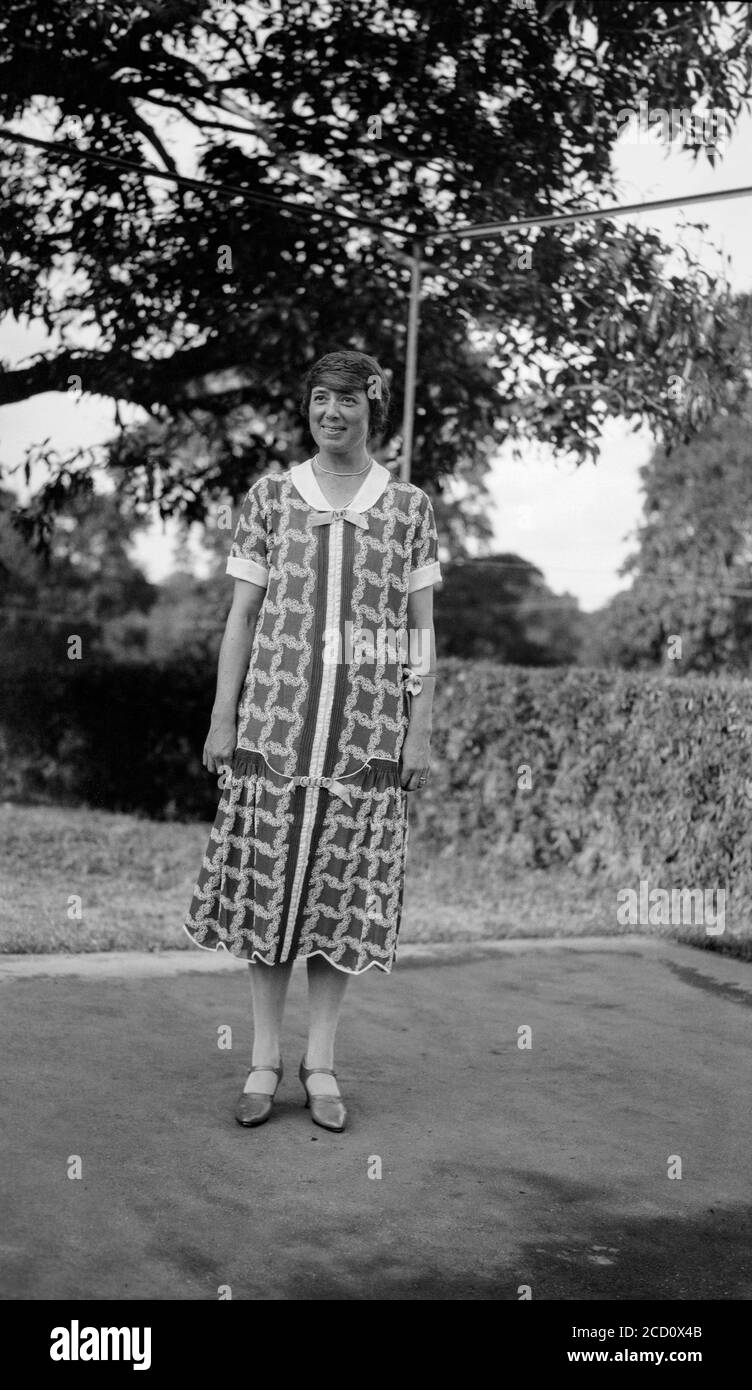 Vintage 1920s English black and white photograph showing a young woman, outside, posing in fashionable clothes of the day. Stock Photo